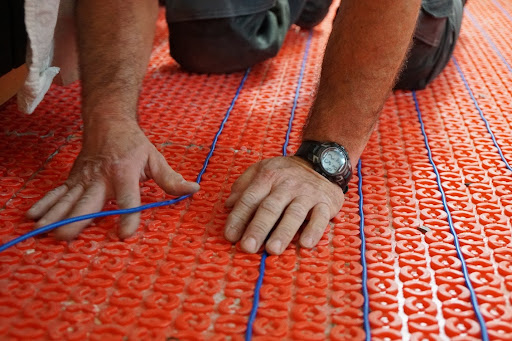 A worker installs wiring for a heated floor system.